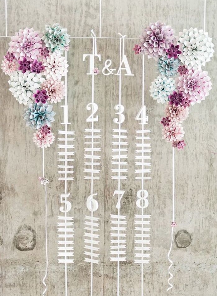plan de table pour mariage, petites étiquettes avec les noms des invités et décoration de fleurs en papier coloré des deux côté