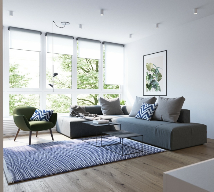 mobilier scandinave, canapé gris et fauteuil vert, tapis blanc et bleu, parquet clair, vue sur un paysage vert