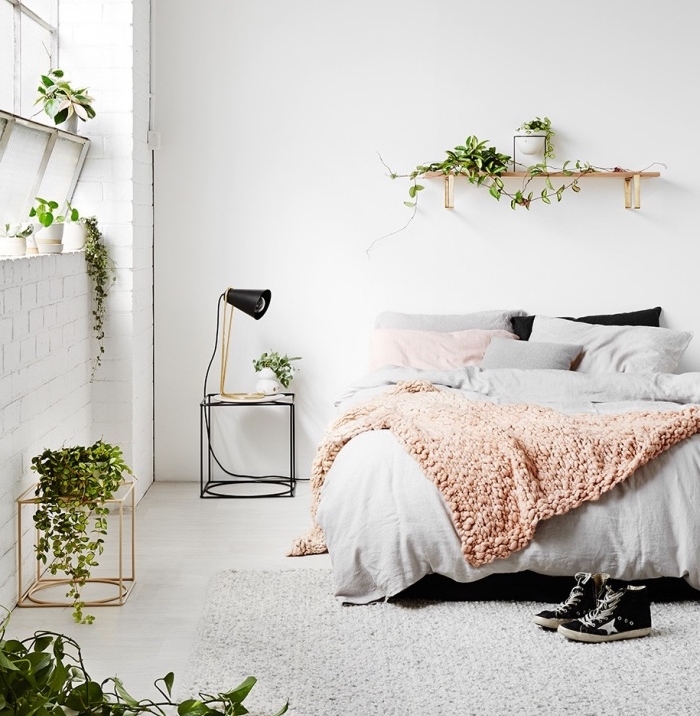 exemple de deco inspiration scandinave, linge de lit gris, couverture plaid saumon, murs blancs et deco de plantes