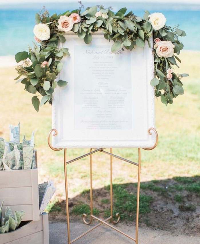 plan de table mariage a imprimer, liste simple imprimée dans un cadre blanc, support doré et guirlande verte avec des roses