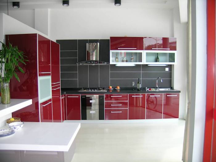 façade cuisine rouge bordeau avec crédence grise, aspirateur inox, petit ilot gris avec plan de travail blanc, sol blanc cassé