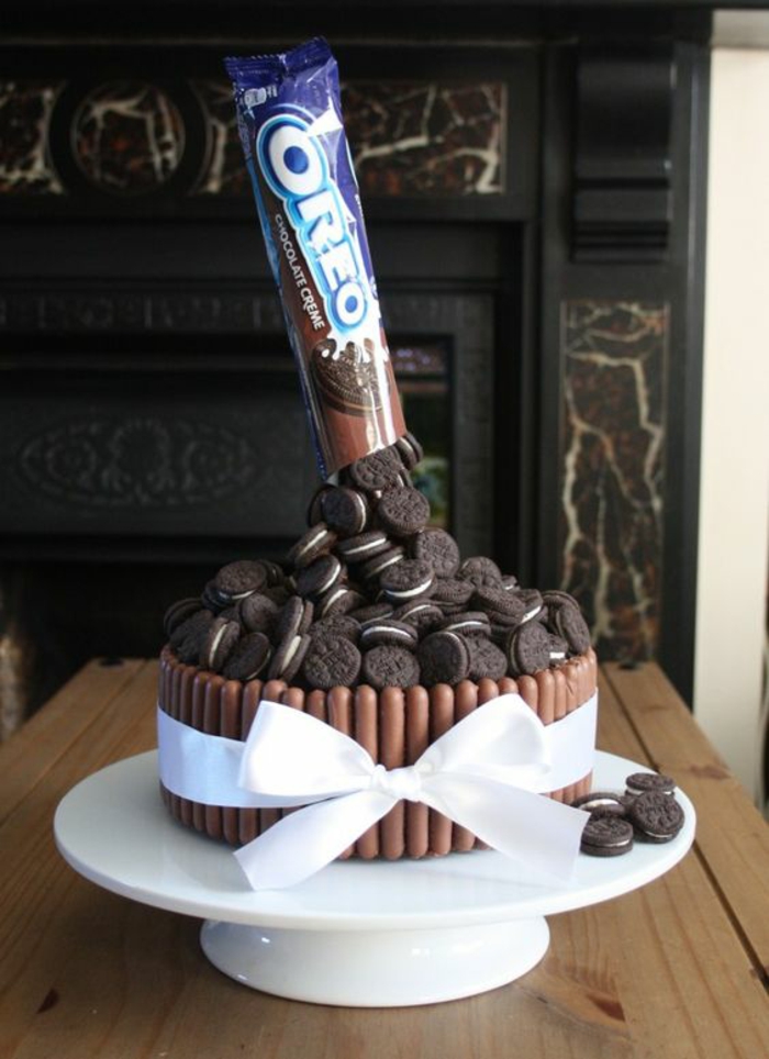 gateau d'anniversaire avec des biscuits au cacao et au lait et des batons au chocolat tenus avec un grand ruban blanc