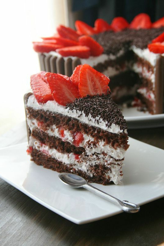 gateau anniversaire aux fraises et au chocolat rempli de crème blanche et morceaux de fraises