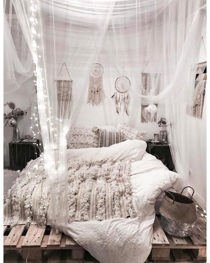 une chambre à coucher bohème chic avec un lit palette à baldaquin et à lumières led