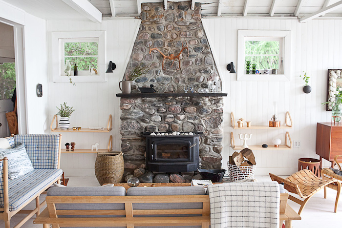 salon cocooning rustique avec cheminée en pierre, bancs en bois avec coussins d assise grises, panier en rotin, lambris blanc