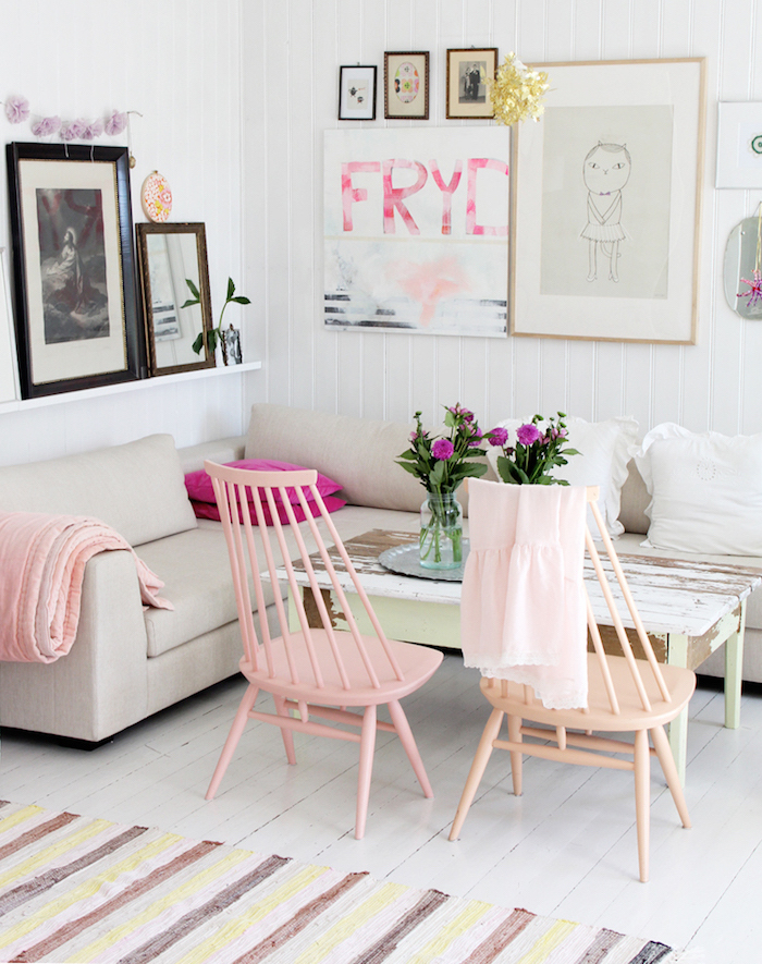 salon aux murs blancs avec cadres photos, canapé d'angle avec coussins décoratifs, table shabby chic en bois peint vert