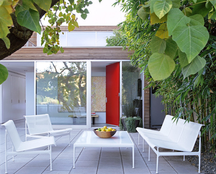 idee salon de jardin sur une terrasse accueillante, revêtement dalles de béton, table basse, canapé et chaises blancs, bambou et autres plantes