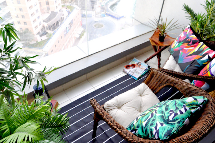balcon deco terrasse petite, carrelage beige, tapis noir à petites rayures blanches, fauteuils en rotin, plantes vertes exotiques