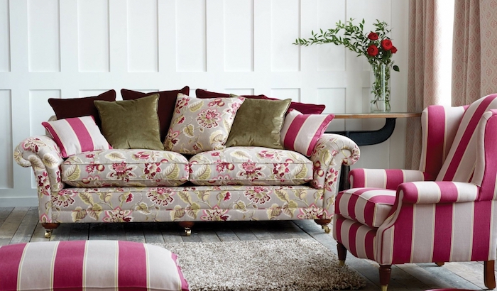 amenagement salon moderne, fauteuil et rabouret blanc et rose framboise, tapis gris, canapé gris imprimé floral, coussins vert, bordeau et framboise