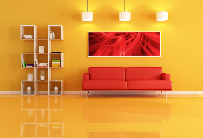 canapé rouge dans un salon jaune, étagère en bois, mur et sol jaune, suspensions blanches, deco salon design simple
