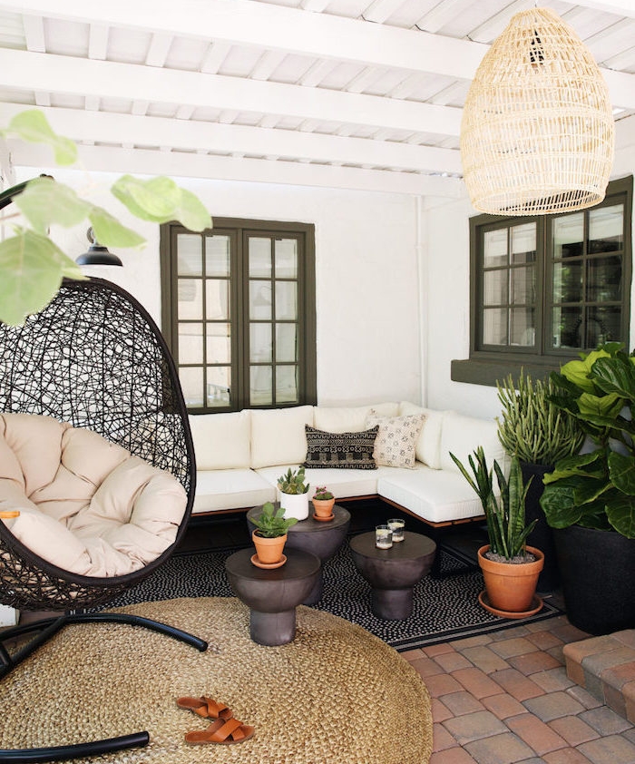 idee salon de jardin oriental avec canapé en bois et métal et coussins d assise blancs, tapis noir et marron, fauteuil noir design intéressant, suspension originale et plantes vertes