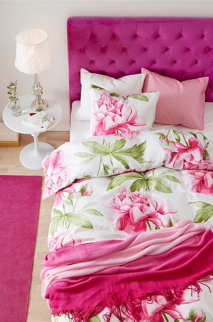 tête de lit, tapis et couverture couleur framboise, linge de lit blanc à imprimé fleuri, parquet clair, table de chevet blanche