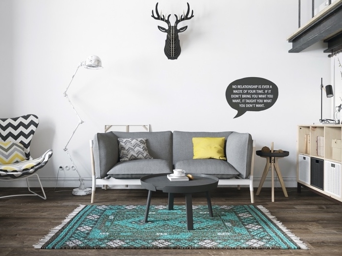 meuble scandinave, canapé et table basse gris, tapis gris et bleu, parquet marron, fauteuil blanc, gris et jaune, deco murale trophée de chasse