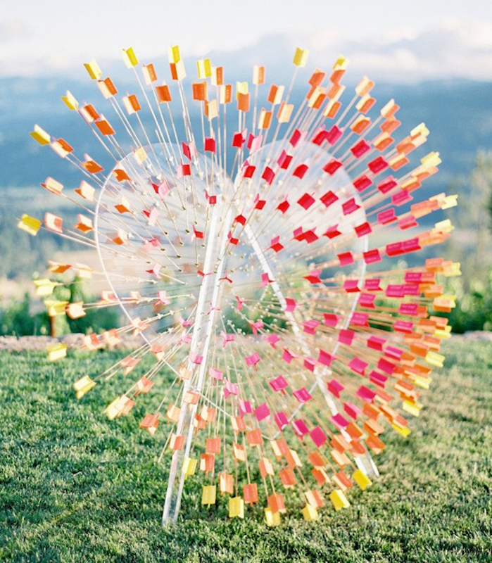 multiples flèches colorées qui passent à travers un grand coeur en plastique avec les noms des invités, plan de table mariage original