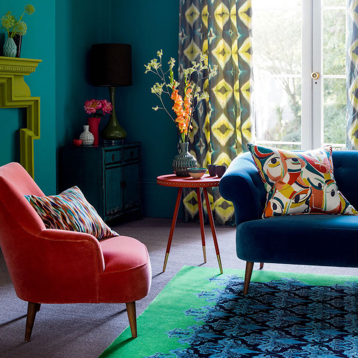 bleue t rouge déco salon avec peinture bleu canard, canapé bleu et tapis bleu et vert, fauteuil rouge, cheminée design, rideaux et coussins décoratifs colorés