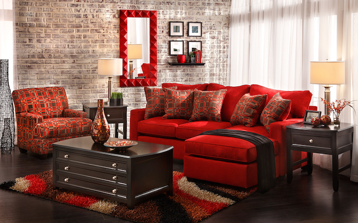 canapé d angle rouge, fauteuil et coussins décoratifs en rouge et marron, tapis coloré, table et parquet marron foncé, mur d accent en briques