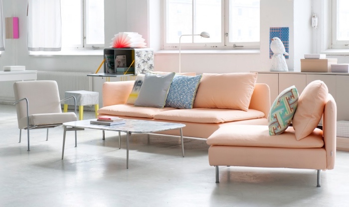 mobilier scandinave pastel, canapé saumon, fauteuil gris, sol blanc et murs blancs, table basse, salon spacieux