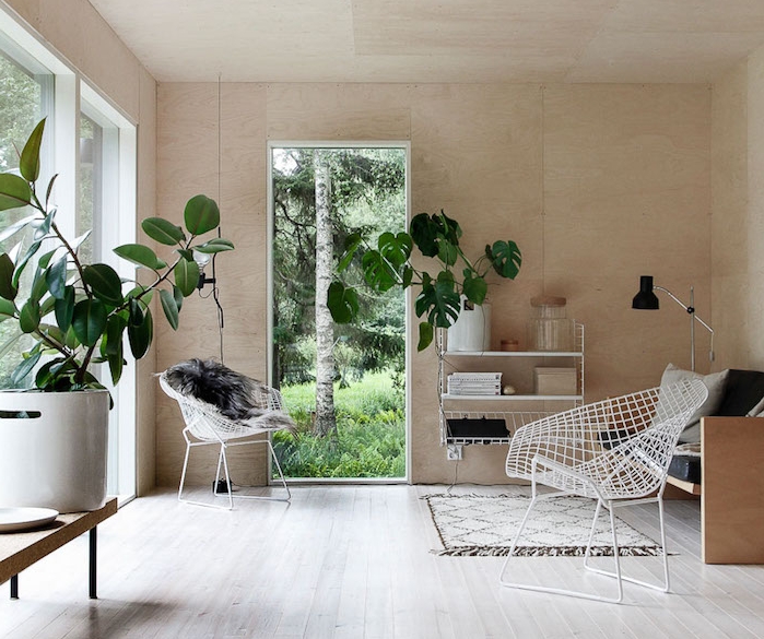 salon cocooning, parquet clair, chaises metalliques blanches, banc en bois, coussins gris, plantes vertes, revêtement mural en bois