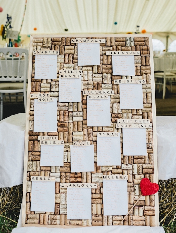 plan de table pour mariage tableau avec fond de bouchons de liège, petites listes blanches invités, coeur rouge