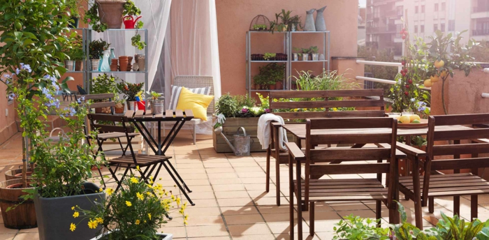 idee terrasse amenagement, table et chaises en bois avec plusieurs plantes vertes, pots de fleurs verts et arbres, étagères rangement fleurs
