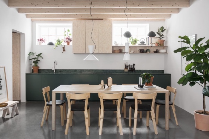 meuble scandinave, table en bois massive, chaises bois et cuir noir, façade cuisine vert foncé et poutres apparentes, deco de plantes vertes