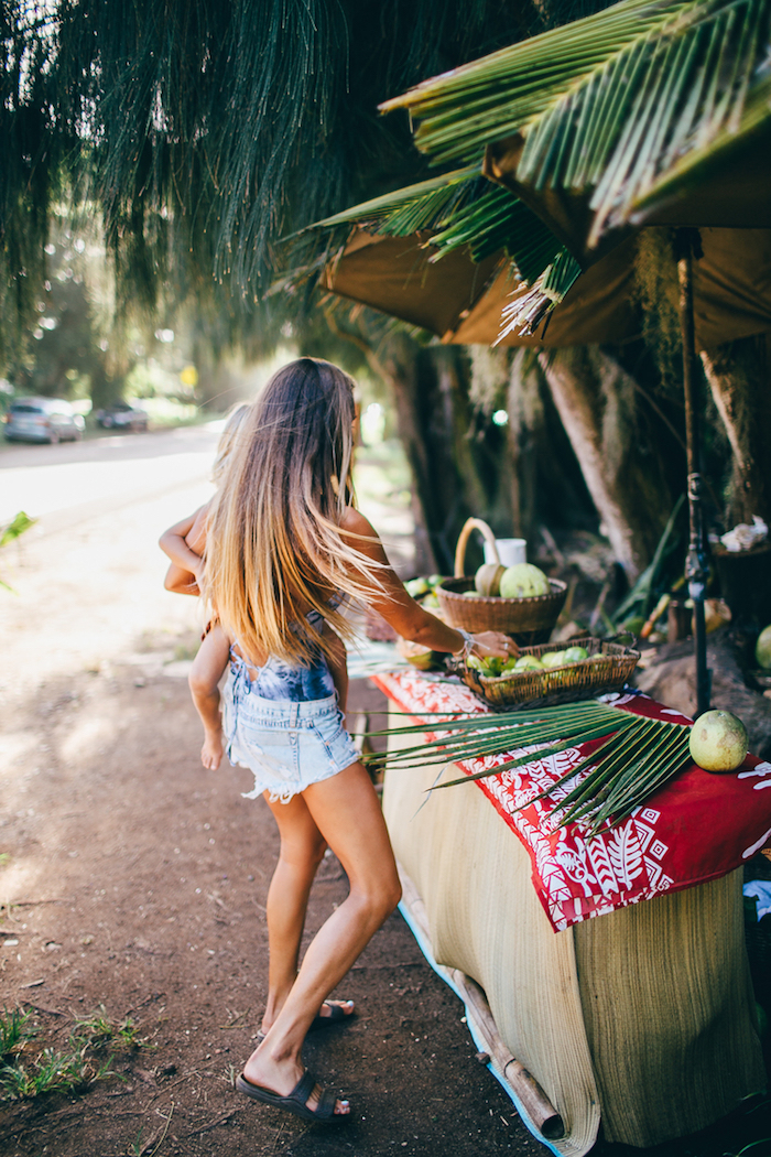 meche-caramel-sandales-femme-noires-cheveux-longs-marché-fruits-shorts-en-denim-débardeur-bleu ombré hair blond, coupe de cheveux longs avec racines foncées et pointes blondes, coiffure cheveux lisses