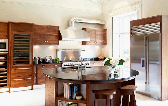 cuisine équipée, plafond et sol blanc, meubles en bois foncé, ilot central rond en bois marron et comptoir noir