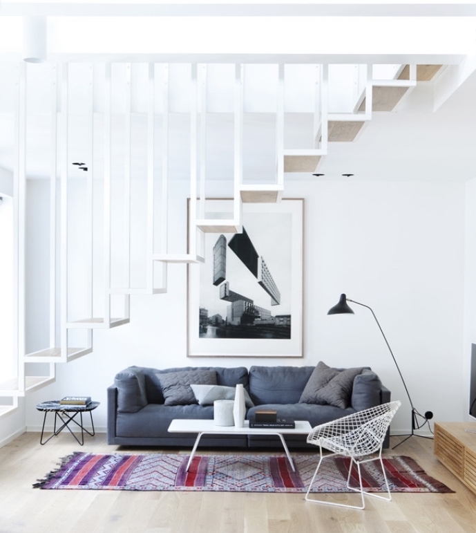 idée de salon scandinave avec canapé gris et tapis oriental, table basse blanche, chaise en métal, escalier design blanc