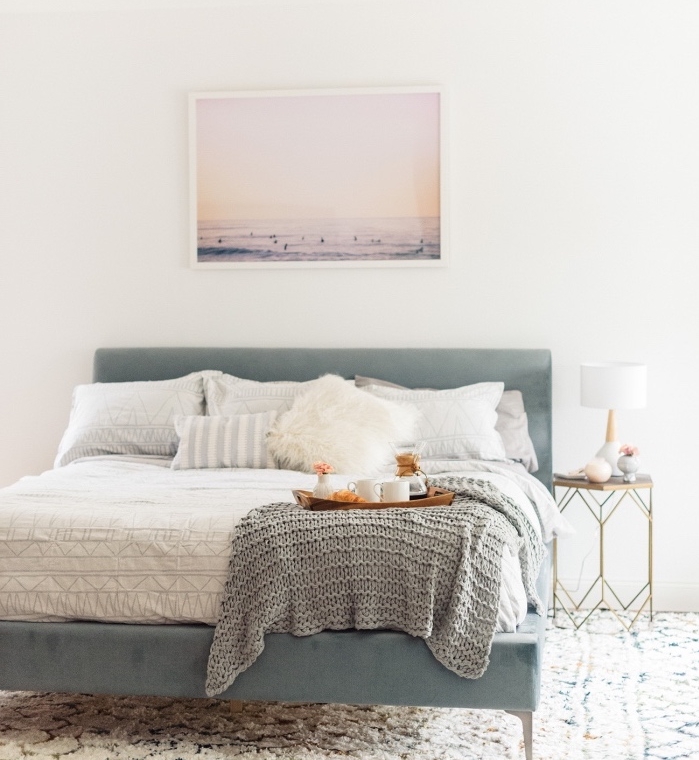 meuble scandinave, grand lit bleu gris, linge de lit blanc, couverture grise, deco photo paysage bord de mer, tapis blanc à motifs géométriques