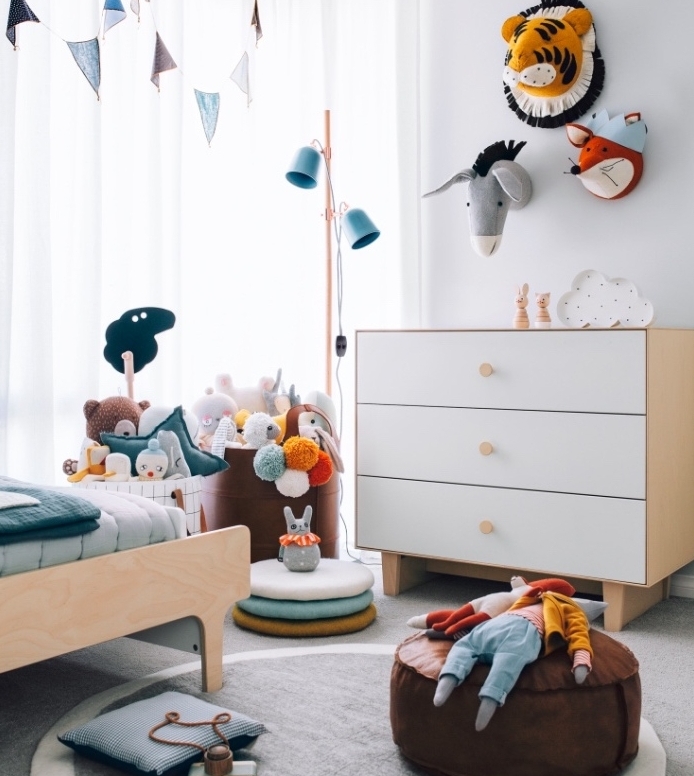 chambre enfant mobilier scandinave, lit et commode en bois, tapis gris, pouf marron, jouets rangés dans des sacs, deco murale animaux