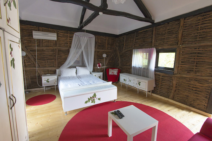 deco chambre, tapis rond en framboise, lit à baldaquin, garde-robe blanche à décoration florale, chaise en tissu rouge