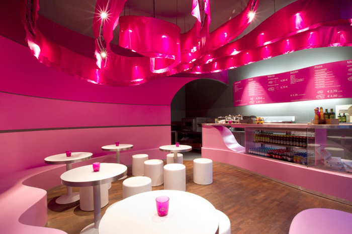 couleur framboise, bar en verre et comptoir rose, murs peints en nuances roses, table ronde avec tabourets blancs