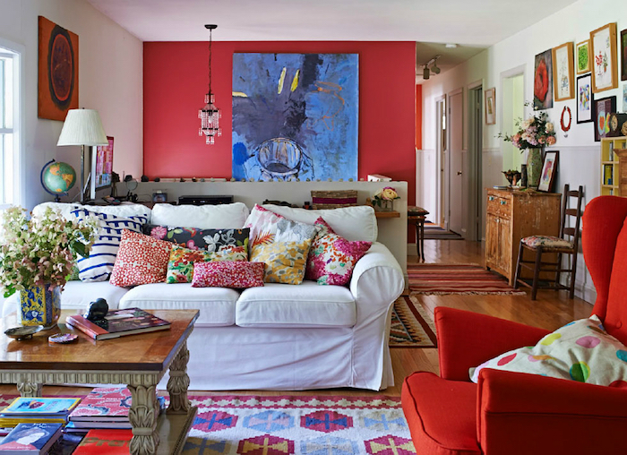 peinture rouge sur un mur d accent, canapé blanc, fauteuil rouge, coussins et tapis colorés, motifs floraux, deco mur de cadres