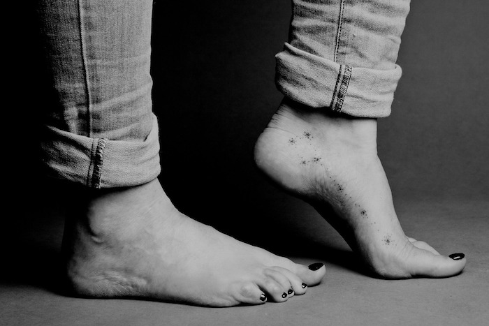 idée dessin en encre discret pour femme, tatouage constellation sur le pied, paire de jeans et manucure noire