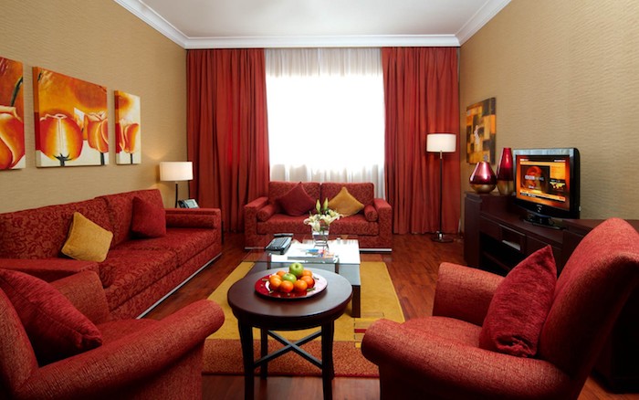 association de couleur, rouge et beige foncé, canapés et fauteuils rouges, tapis jaune et orange, meuble tv marron