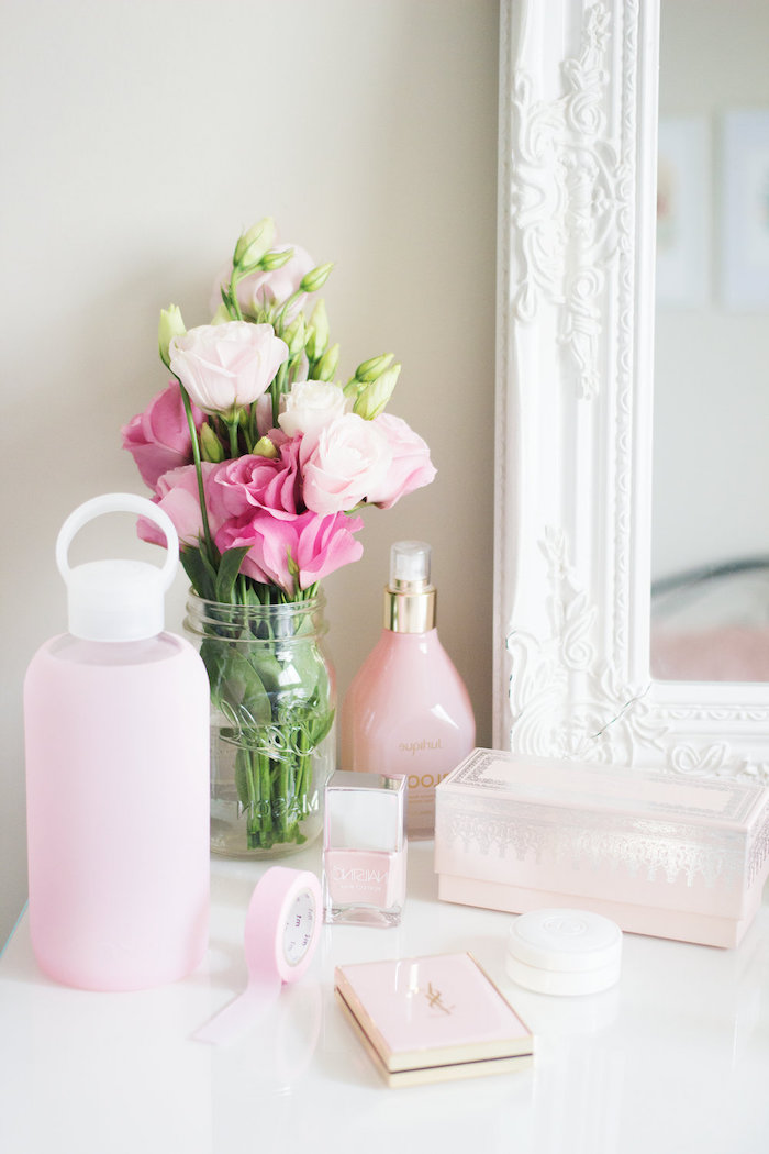 coin de beauté dans une chambre féminine, objets décoratifs en blanc et rose pastel, bouquet de roses