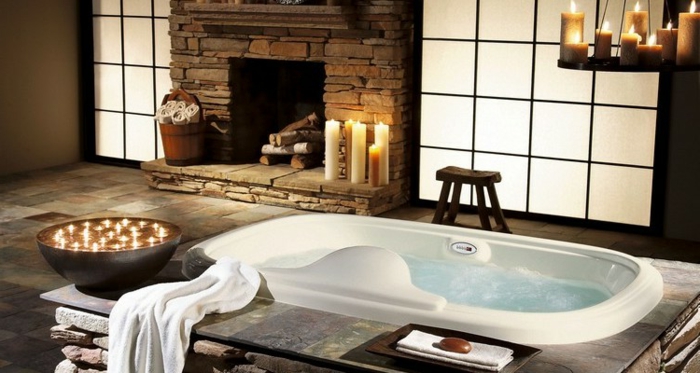 salle de bain zen, cheminée en pierre, bougies allumées, baignoire à encastrer, bol noir avec bougies flottantes