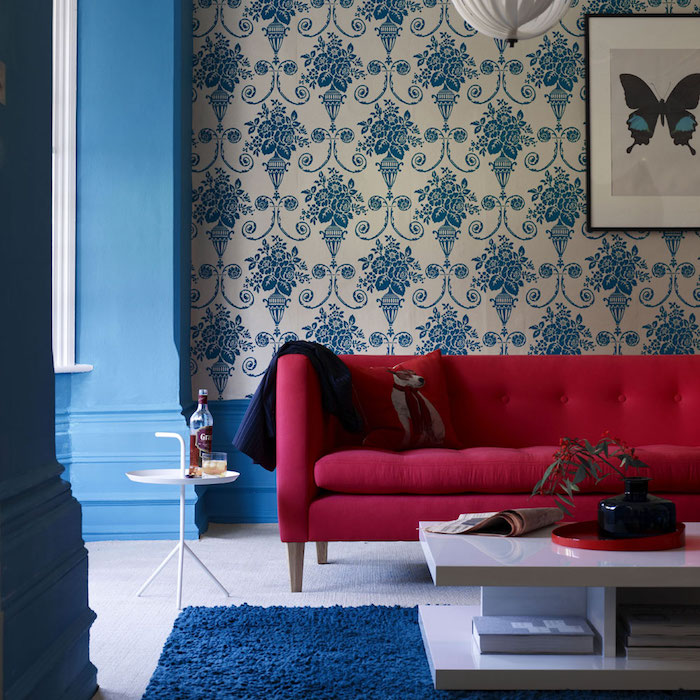 salon bleu et rouge, accord de couleurs, papier peint blanc à motifs floraux bleus, tapis bleu et table basse blanche, canapé rouge, ambiance vintage