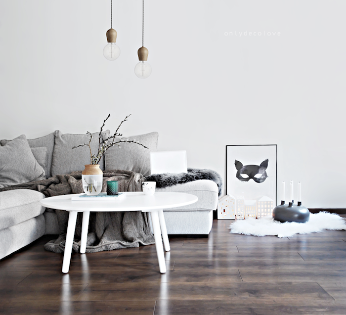 coussin cocooning, plusieurs coussins gris sur un canapé blanc table basse blanche et, tapis de fausse fourrure blanche, jeté gris, suspensions originales