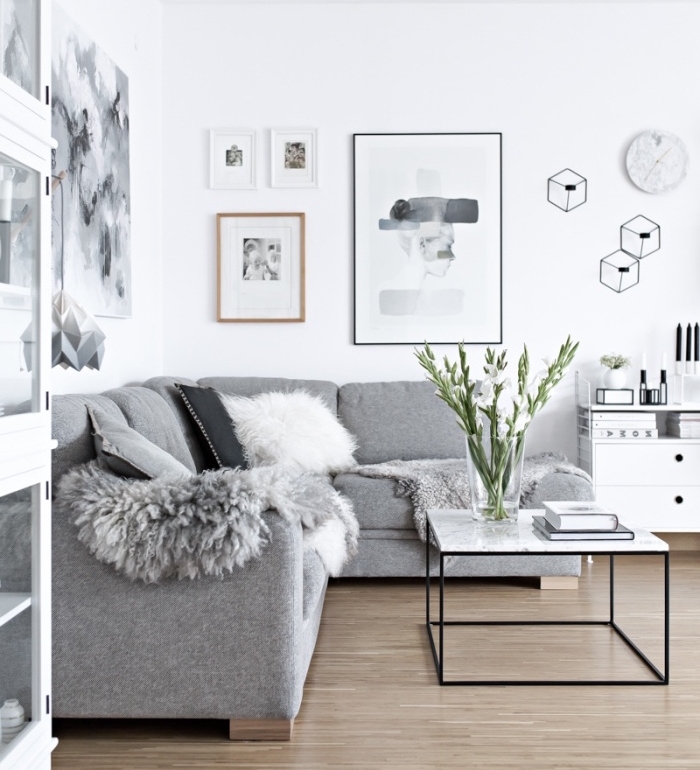 meuble scandinave canapé gris, peau animal grise, mur blanc, table basse en metal et plateau de marbre, deco murale noir et blanc, oeuvres graphiques