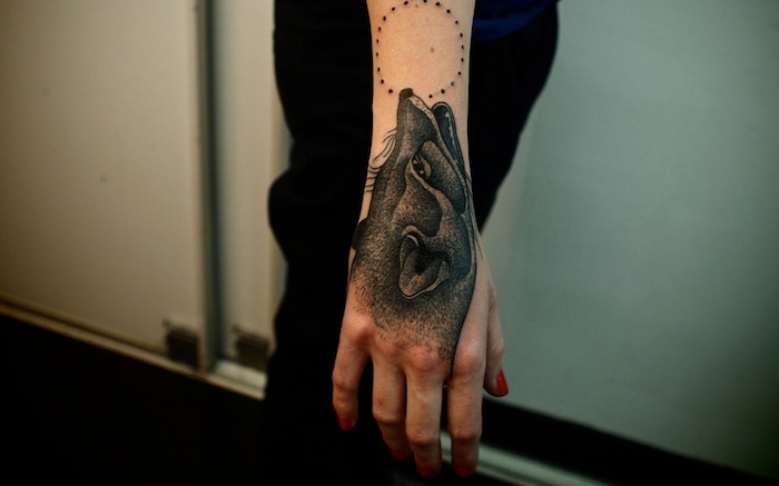 tatouage loup femme, manucure rouge et tatouage sur la main à design loup et lune