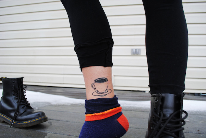 tatouage femme, dessin en encre à design tasse de café, bottines noires en cuir pour femme, pantalon noir