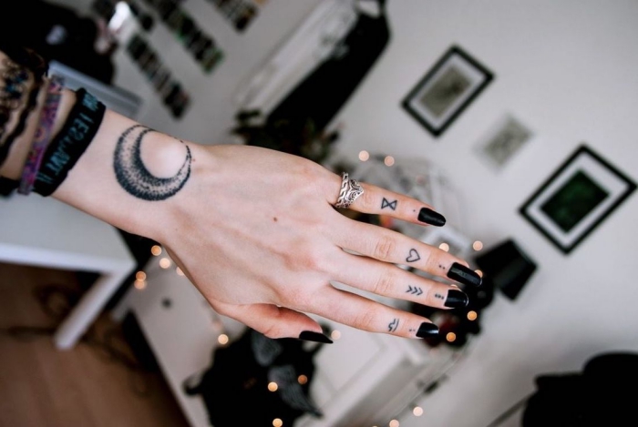 petit tatouage, dessin en encre sur les doigts, manucure noire, bague auriculaire femme