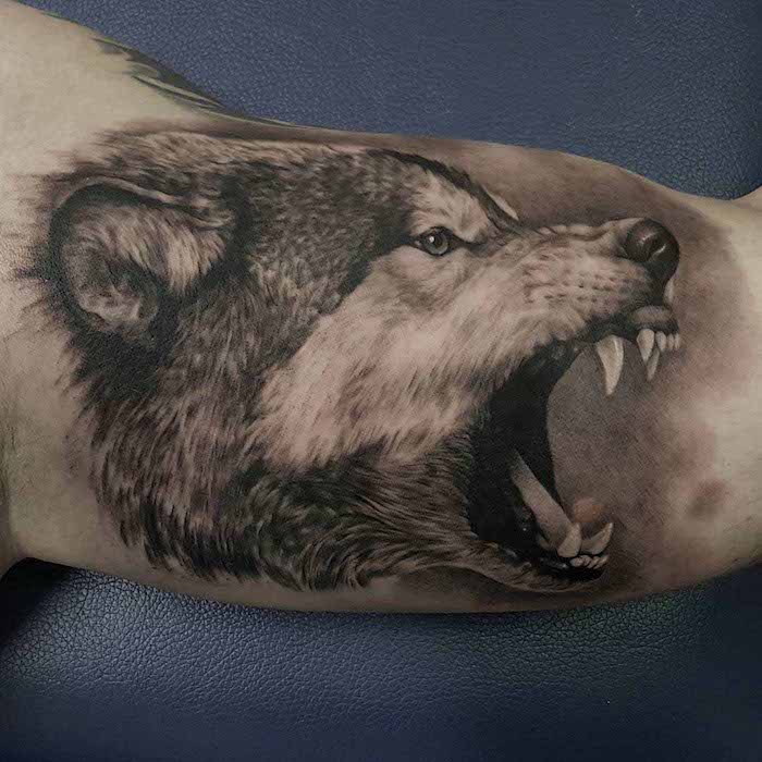 tatouage bras homme, dessin en encre à motif loup féroce, art corporel pour homme à dessin tête de loup
