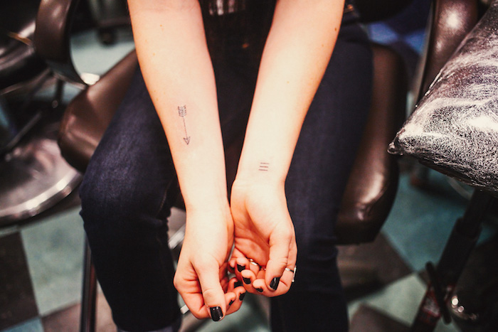 tatouage femme bras, chaise en cuir noir, pantalon noir femme, manucure noire, petit tattoo sur le poignet