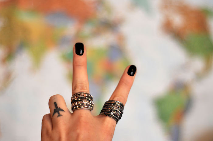 esprit d'aventurier, petit avion en encre gravé sur le doigt, manucure noire, idée tattoo pour femme