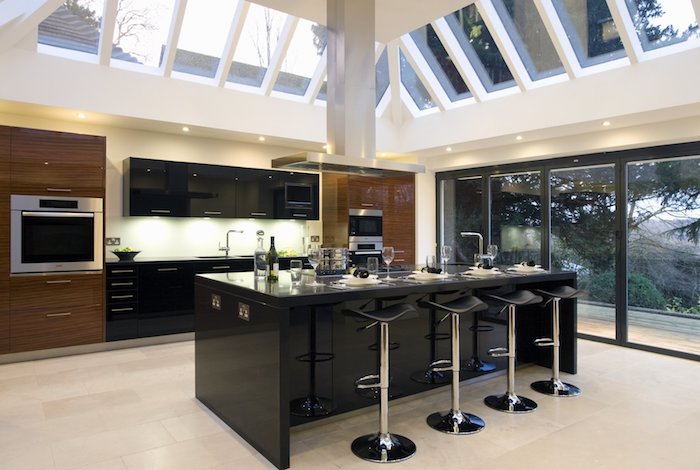 meuble de rangement cuisine, portes coulissantes en cadre noir vers le jardin, plafond avec fenêtres et éclairage led