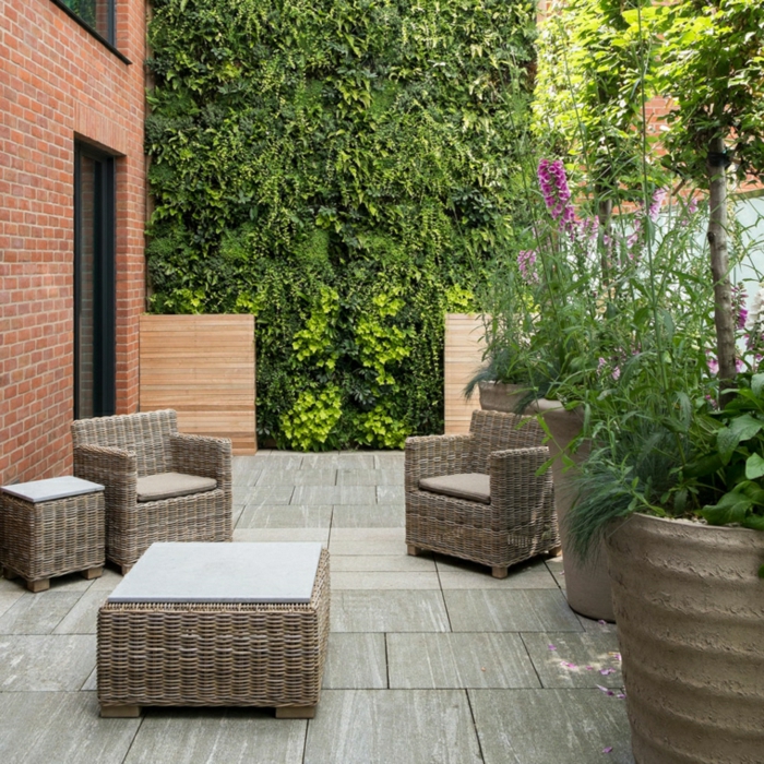 idee salon de jardin tressé, dalles de béton en revêtement, fauteuils et table en rotin, mur végétale plantes vertes