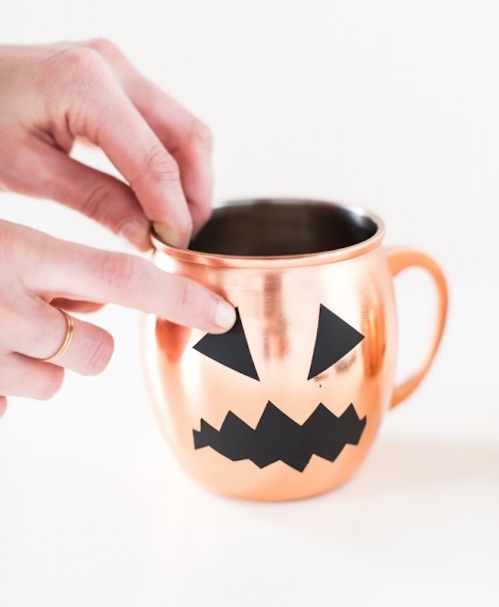 activité manuelle halloween, une tasse à thé couleur rose gold avec des yeux et bouche silhouette noire