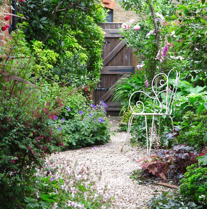 cailloux blanc, idée comment décorer son jardin, coin vert dans la cour avec porte en bois marron foncé